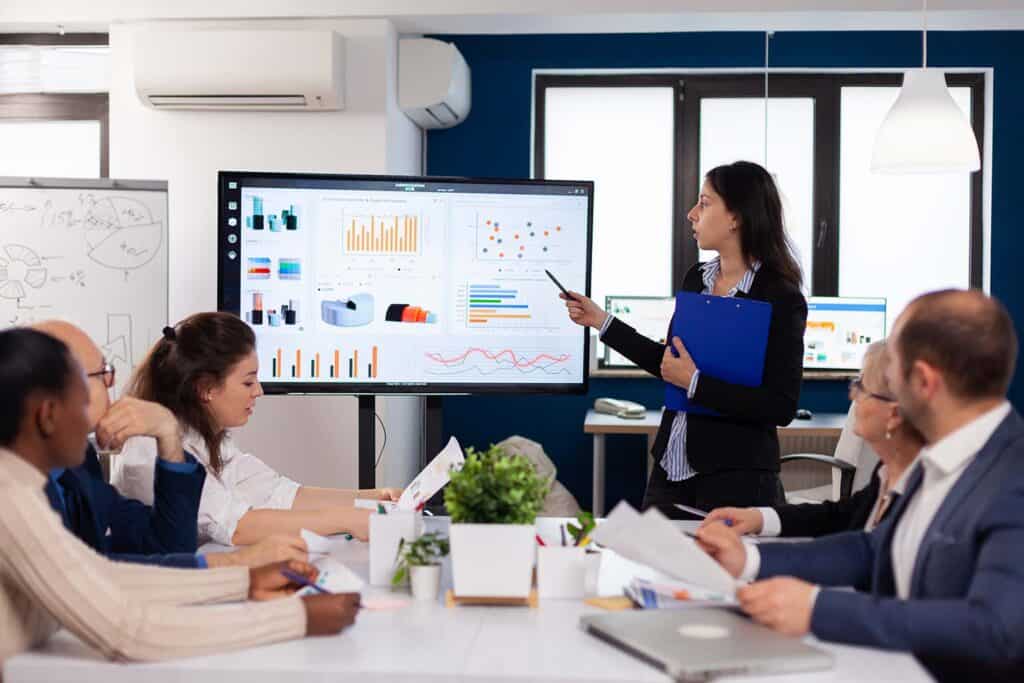 jovem-lider-de-equipe-em-uma-grande-corporacao-informando-colegas-de-trabalho-apontando-para-o-grafico-reunindo-a-equipe-corporativa-goobec